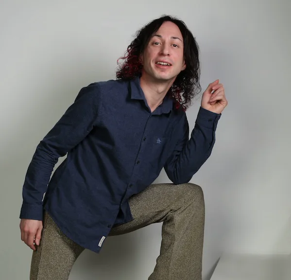 BexX, Bristol singing teacher, posing in a navy shirt against a plain studio wall
